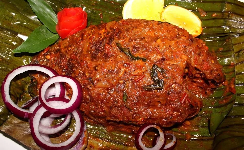 a piece of meat with onions and lemons on a leaf